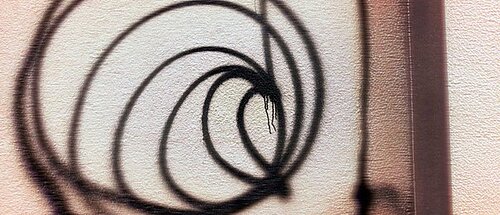 Braune Graffito-Bögen ähnlich eines Schneckenhauses an heller Hauswand