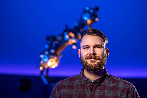 Portrait Christian Schönherr mit Sternprojektor im Hintergrund