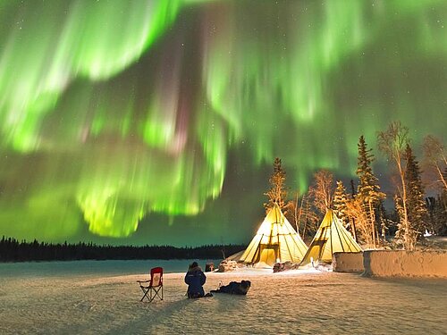 Grünschillerndes Polarlicht über zwei Zelten in nördlicher Schnee-Einsamkeit