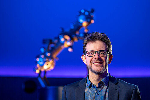Portrait Dirk Schlesier mit Sternprojektor im Hintergrund