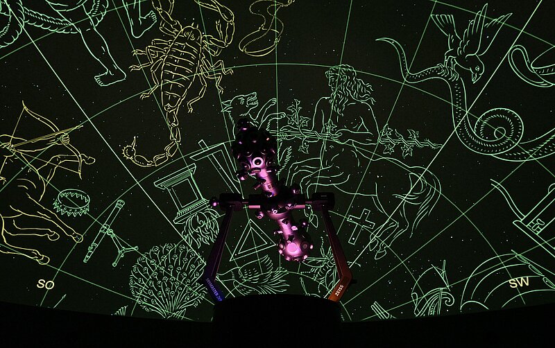 Sternprojektor vor dunkler Planetariumskuppel mit Sternbild-Zeichnungen und Sternen des Südsternhimmels