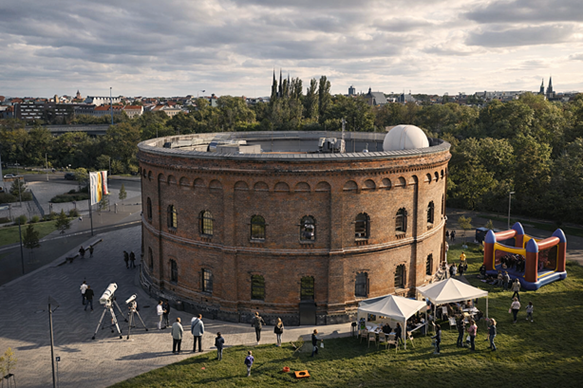 Teleskope, Hüpfburg und Veranstaltungszelte mit Gästen vor Ziegelsteinrundbau mit vielen Fenstern