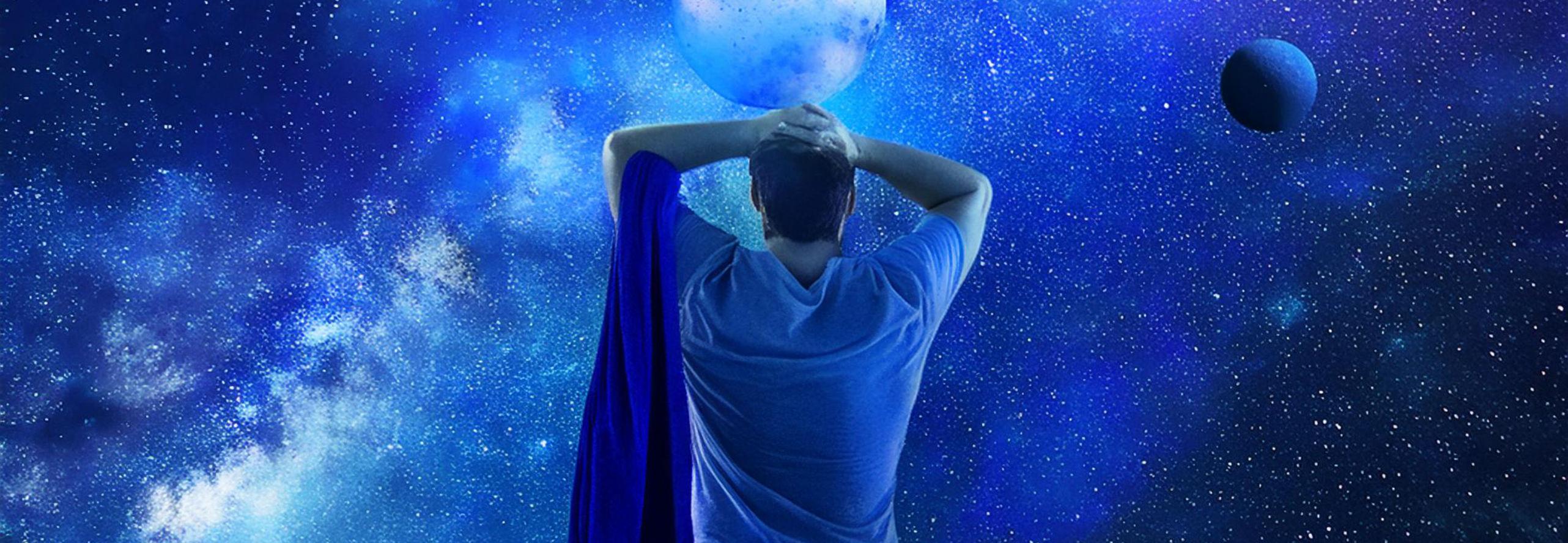 Eine Person mit Handtuch über der linken Schulter schaut in den tiefblauen Sternenhimmel.