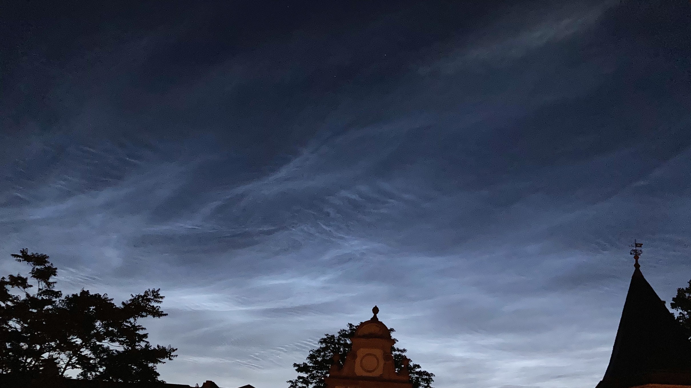 Helle Wolken im Form von zarten Bändern und Schlieren am dunklen Abendhimmel