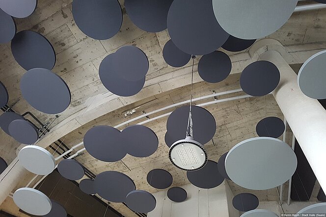 An der Decke im Foyer des Planetariums hängen hell- und dunkelgraue schalldämmende Scheiben in verschiedenen Größen wie schwebende Himmelskörper.